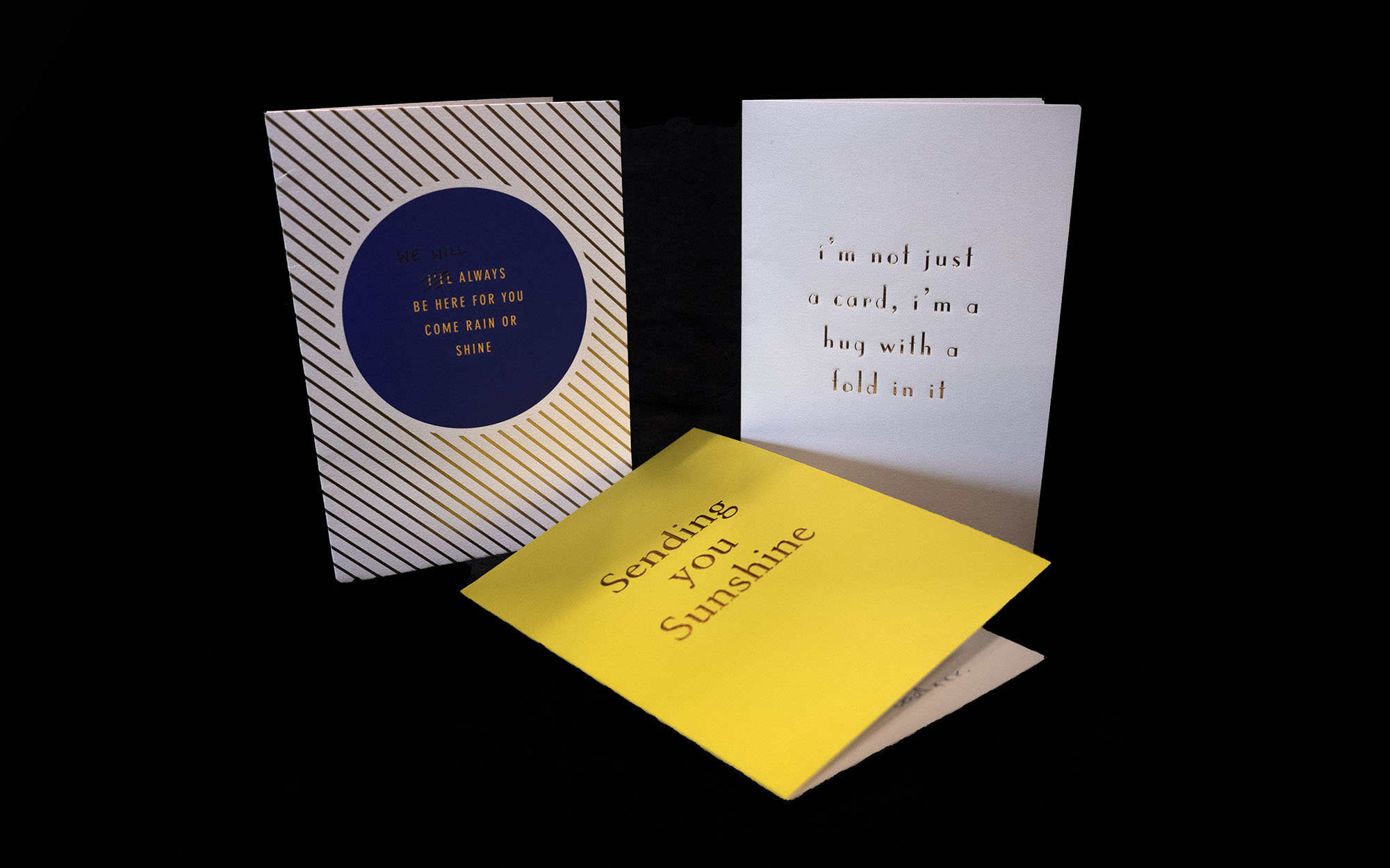 Three greeting cards: one says "Sending you sunshine", another one says "I'm not just a card, I'm a hug with a fold in it", and the other says "I'll always be here for you come rain or shine" with "I'll" crossed out and written "we will"