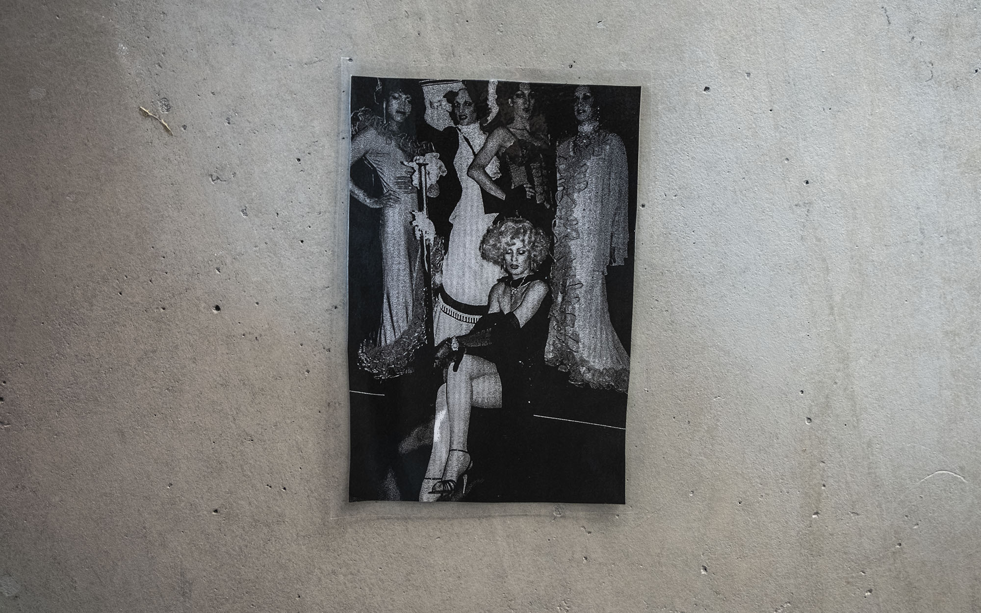 Photo hanging on a concrete wall featuring five people in evening dress