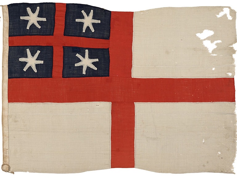New Zealand Company / United Tribes flag, 1839, maker unknown. Gift of Andrew Haggerty Richard Gillespie, 1967. CC BY-NC-ND 4.0. Te Papa (GH002925) Weathered flag. It comprises of a white background with a red symmetric cross and in the top left quadrant a blue background with a smaller red symmetric cross and white stars in the quadrants