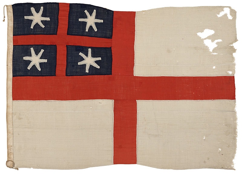 Weathered flag. It comprises of a white background with a red symmetric cross and in the top left quadrant a blue background with a smaller red symmetric cross and white stars in the quadrants