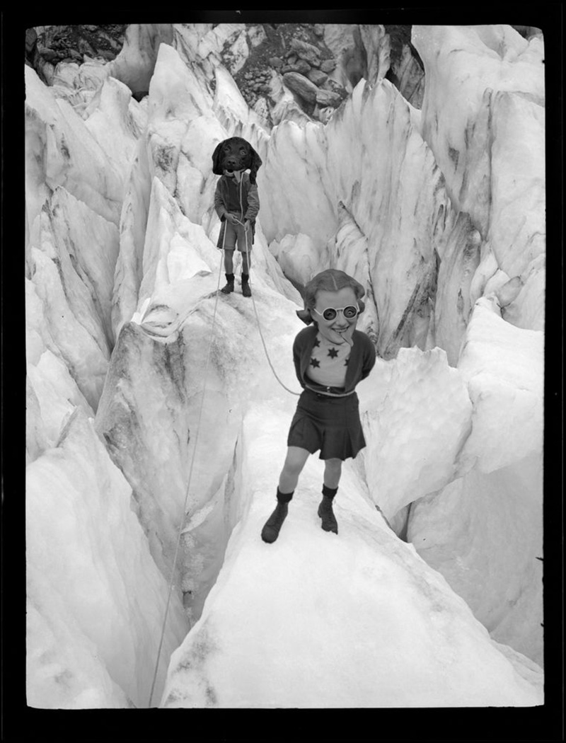 Photo montage of two people standing on an icy crevasse, one has the head of a dog with its tongue hanging out and the other has an enlarged head of a woman with the dog’s tongue hanging out of her mouth. They have swapped eyes
