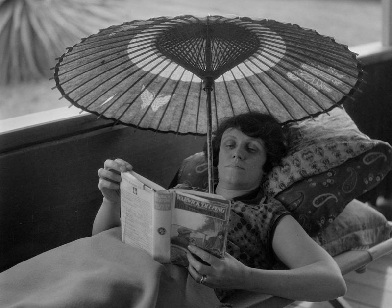 A lady reads inside under a parasol