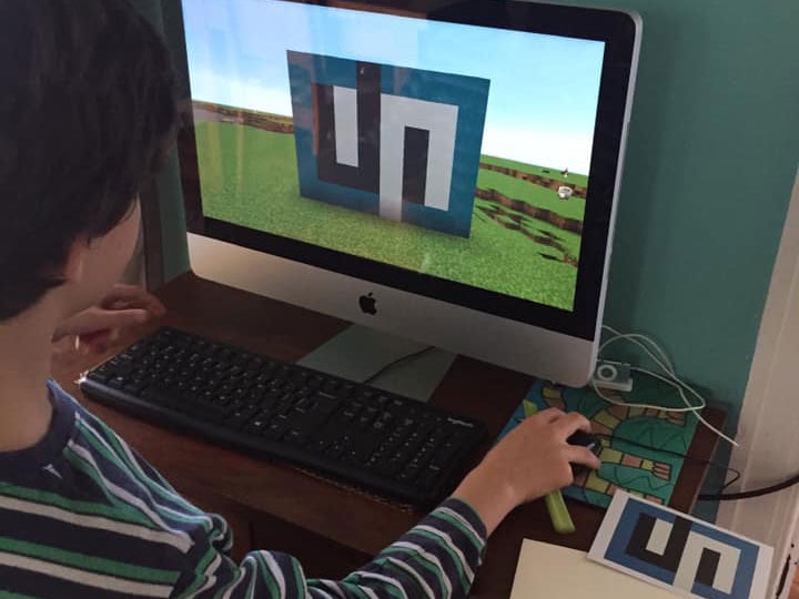 A little boy copies an artwork in a Minecraft game