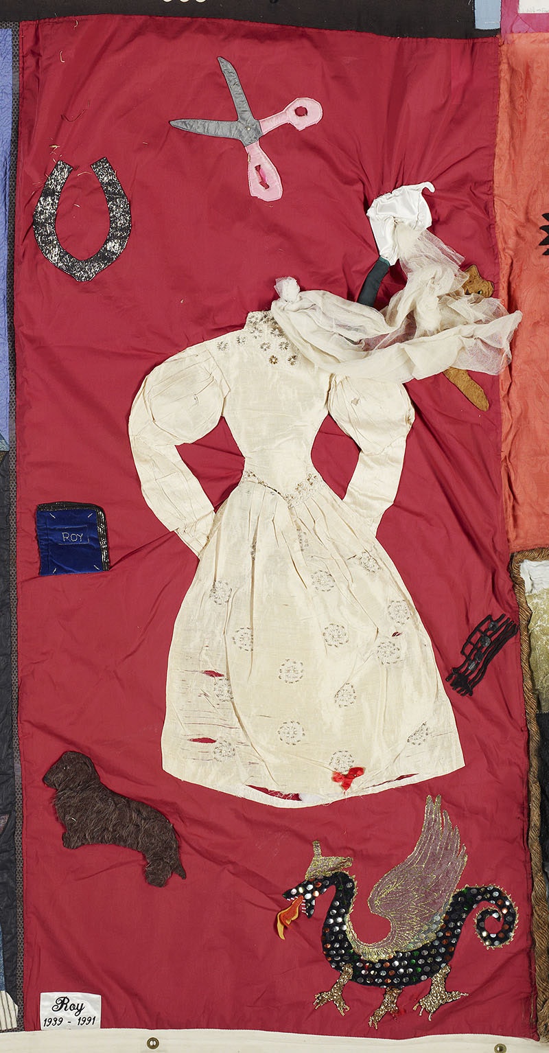 A panel from the NZ Aids Memorial Quilt. It is red with a dress on it and fabric scissors and a horseshoe and dog sown in