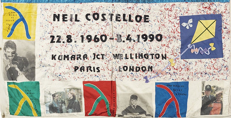 A panel from the NZ Aids Memorial Quilt. It contains multiple photos as well as four signs of different colours saying ‘God bless Welly queens’