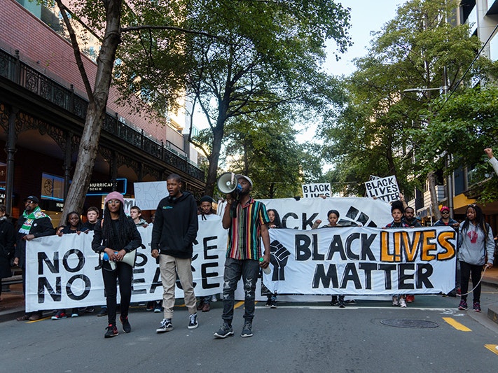 Third Culture Minds volunteers at Black Lives Matter march, 2020. Photo by Nigel Wong, courtesy of Third Culture Minds People in front of a Black Lives Matter banner marching in a tree-lined street