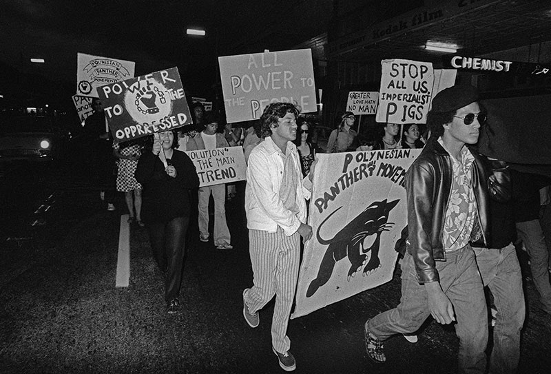 A group of people march in a line holding placards