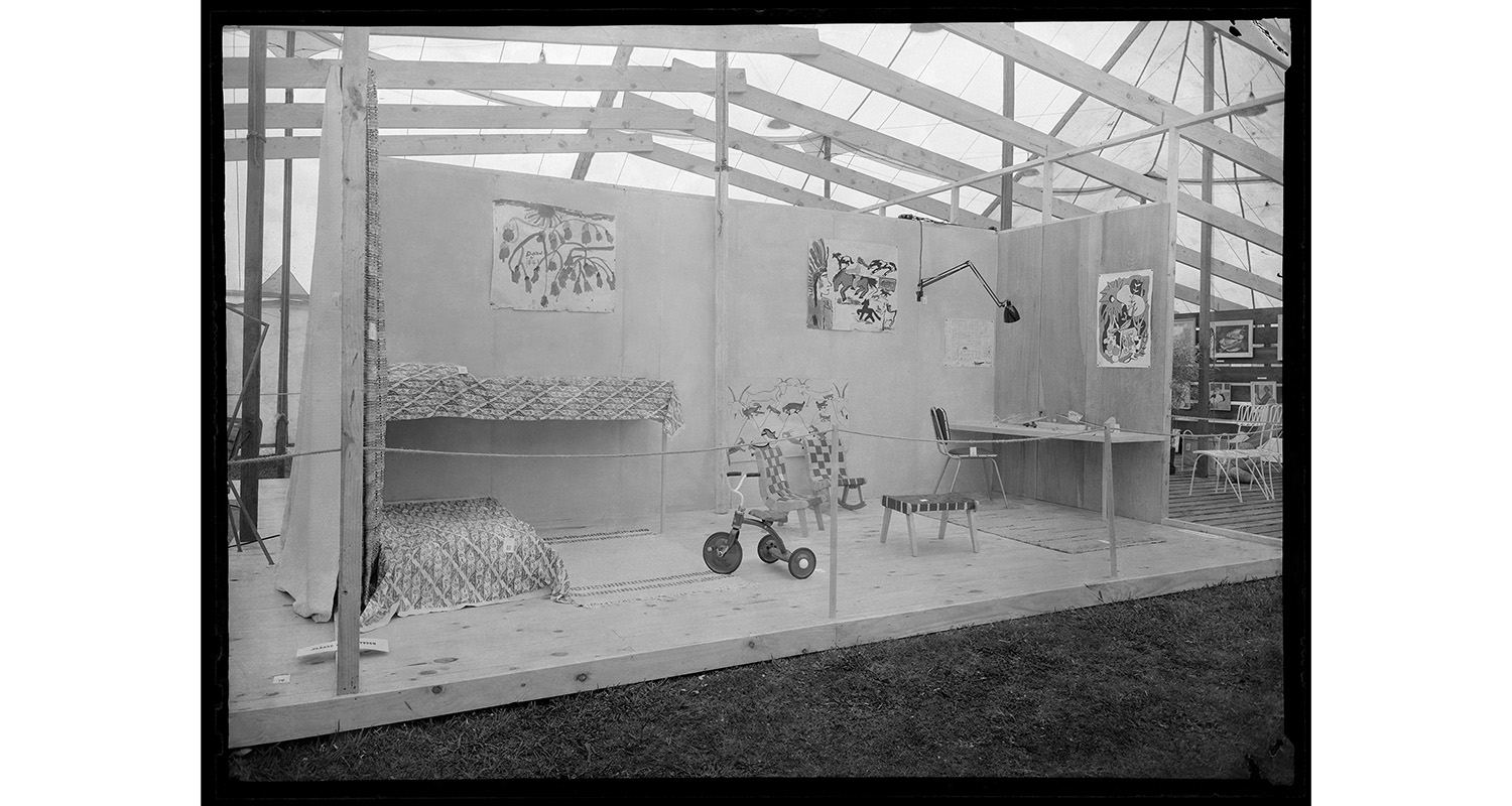 Black and white photo of a set of a room on a pallet floor in a marquee tent