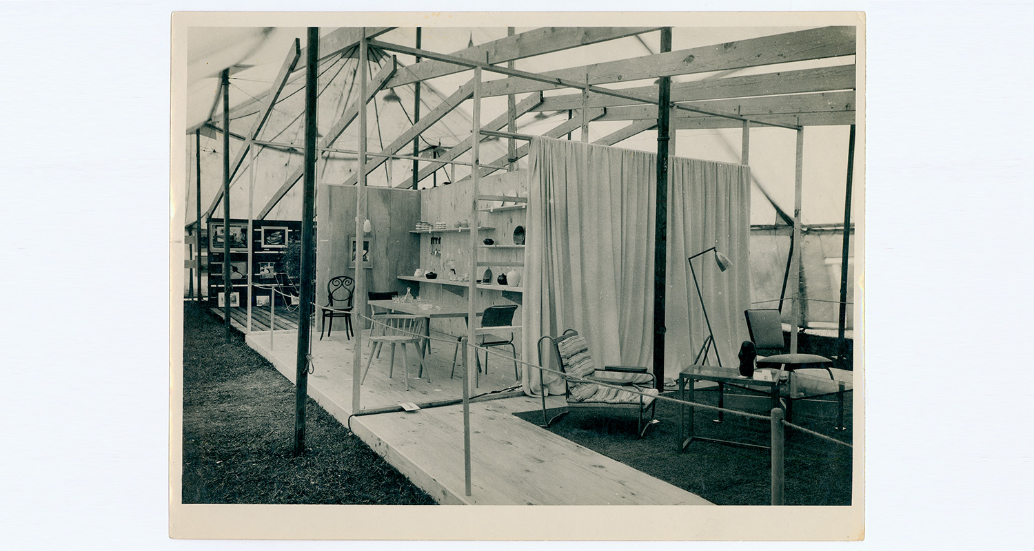 Black and white photo of a scene of a room on pallets in a marquee tent