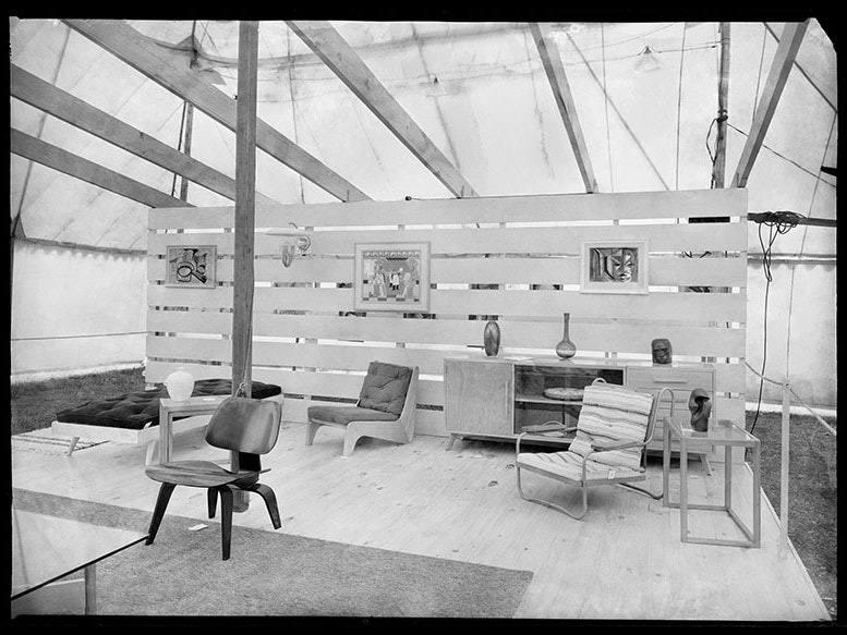Frank Hofmann, Art and Design exhibition, 1952, black and white negative. Gift of the Frank Hofmann Estate, 2016. Image restored by Jeremy Glyde. Te Papa (B.078102) Display of a mid-century living room set up in an exhibition, with chairs, painting on the wall, and a sideboard