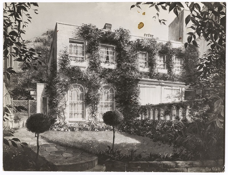 Photo of a large house, with creepers growing on its facade, and large windows. A manicured lawn is in front of the house