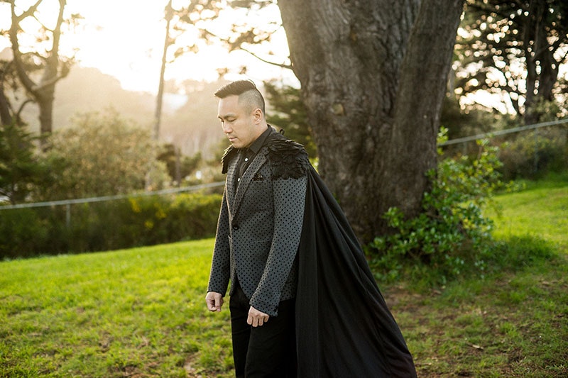 Portrait of Chris Tse wearing a jacket with a black cape and feathered shoulders