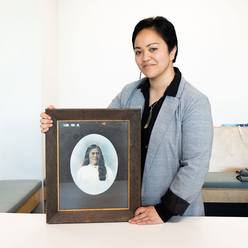 Migoto standing with a framed photograph of her grandmother