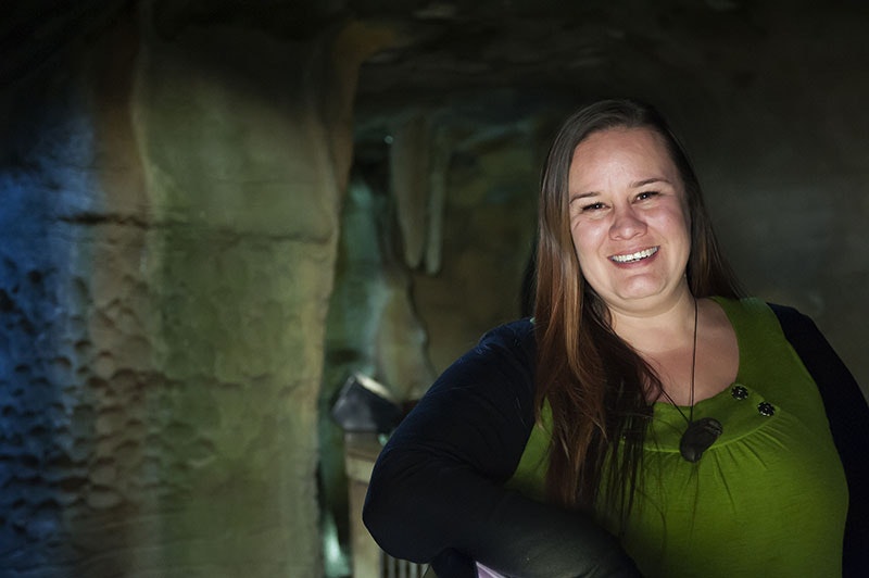 Amber, smiling, poses for a photo in a cave