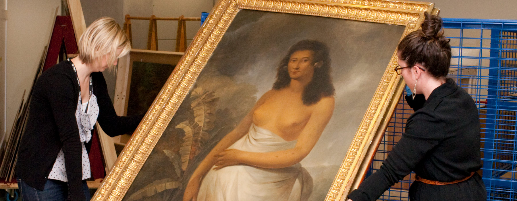 Two women holding a large painting