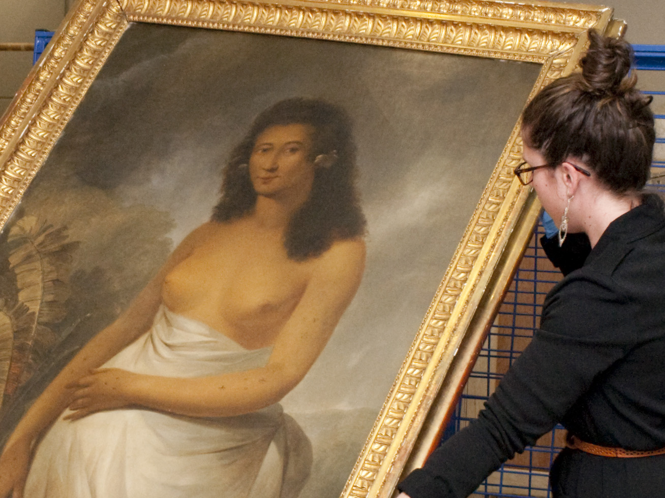 A woman holding a painting wearing blue gloves