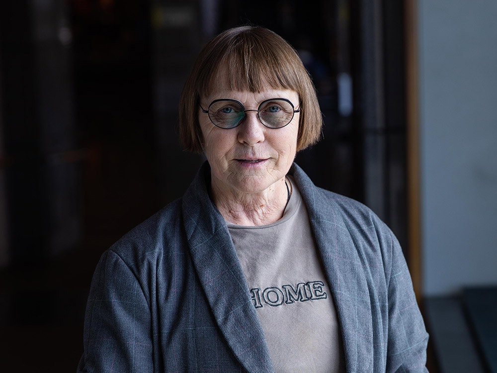 Judith Jones. Photo by Jack Fisher. Te Papa A photo of a woman wearing glasses in a dark hallway