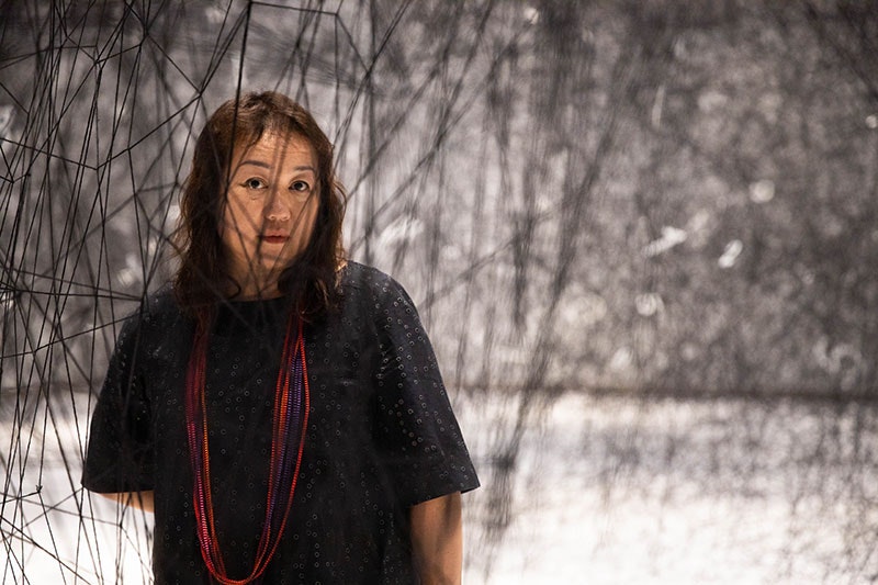 Chiharu Shiota standing among The web of time