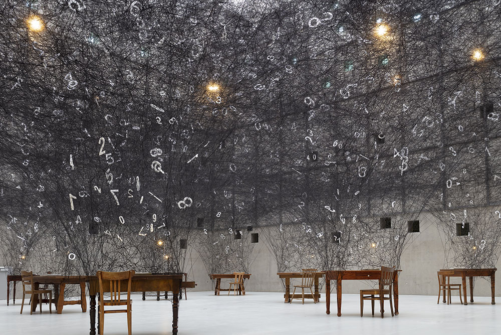 Detail of the artwork ‘Counting Memories’, featuring black strands of wool and white numbers hanging in the voids between the threads