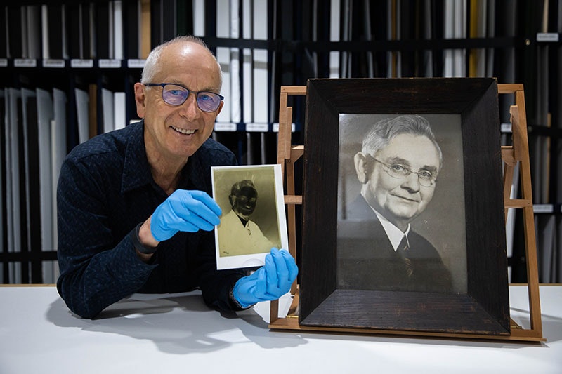 Curator Athol McCredie holds up the negative of the photo of Michael Joseph Savage