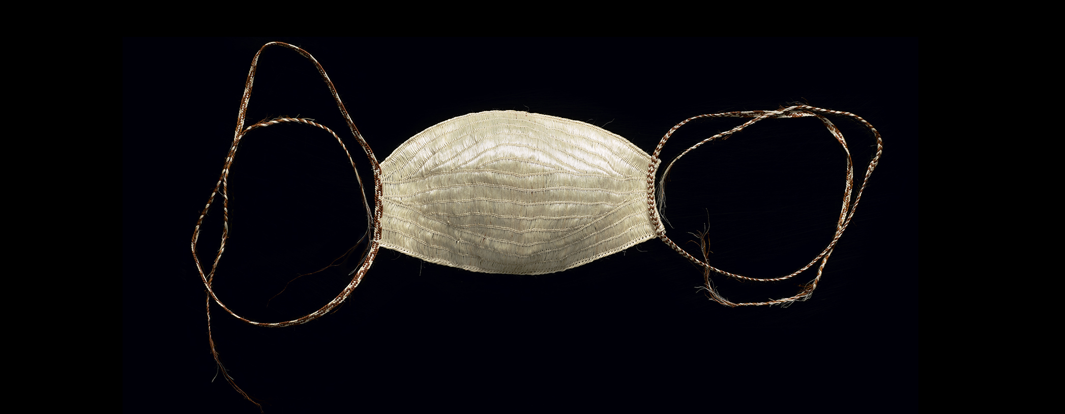 A face mask woven from flax muka on a black background