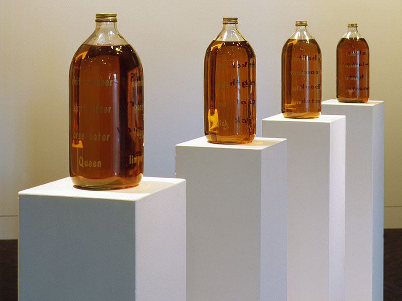 Four large bottles containing beer stand on four plinths