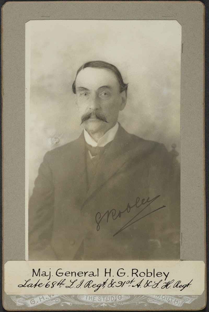 Photo of the a man with arched eyebrows and a moustache, with his name listed underneath as Maj. general H.G. Robley and his two regiments. He has signed it.