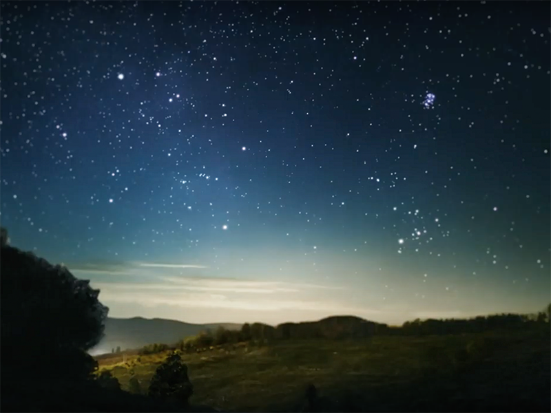 A starry sky over a darkened landscape