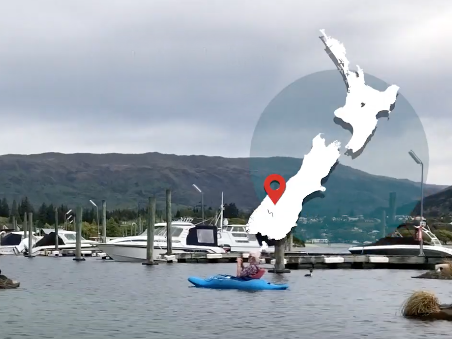 People in boats on a lake with a map of New Zealand overlaid on the right-hand side