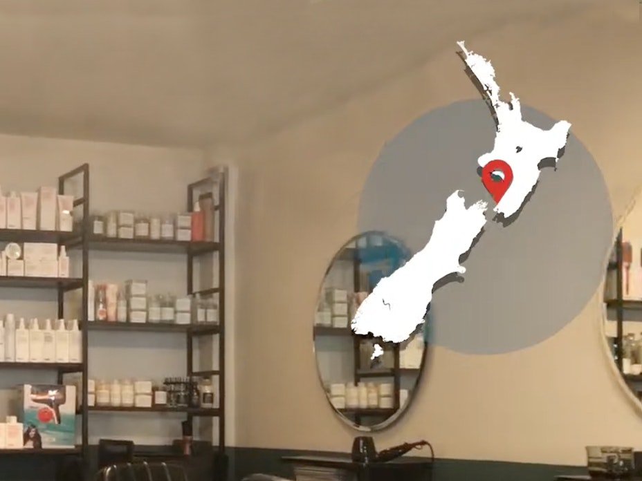 A map of New Zealand overlaid on an interior shot of a hairdresser