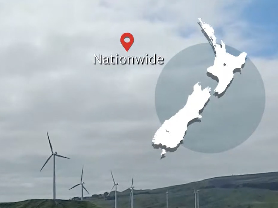 A windfarm on a grey day with a map of New Zealand overlaid in the top right-hand corner