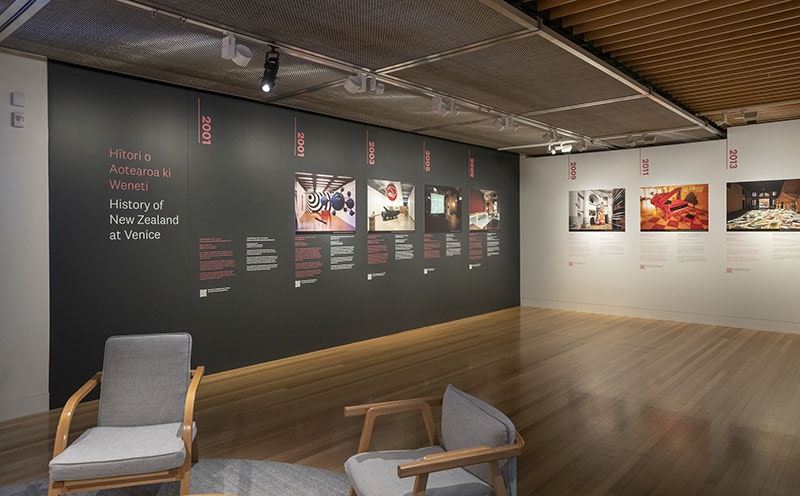 A gallery with large photos on the wall and chairs in the foreground