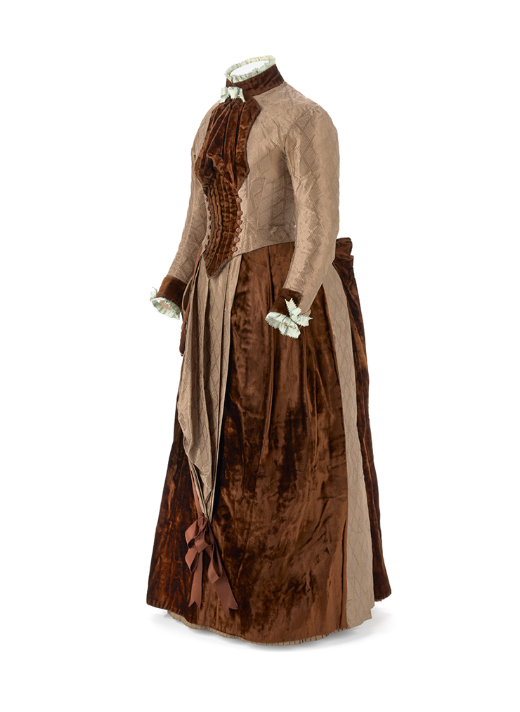 An 1850s brown and cream dress on a mannequin with a white background