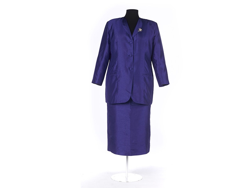 A purple suit jacket and skirt with a silver brooch, on a white background