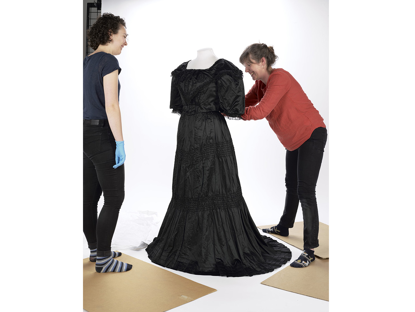 Two people dressing a dressmaker's dummy with white and black material