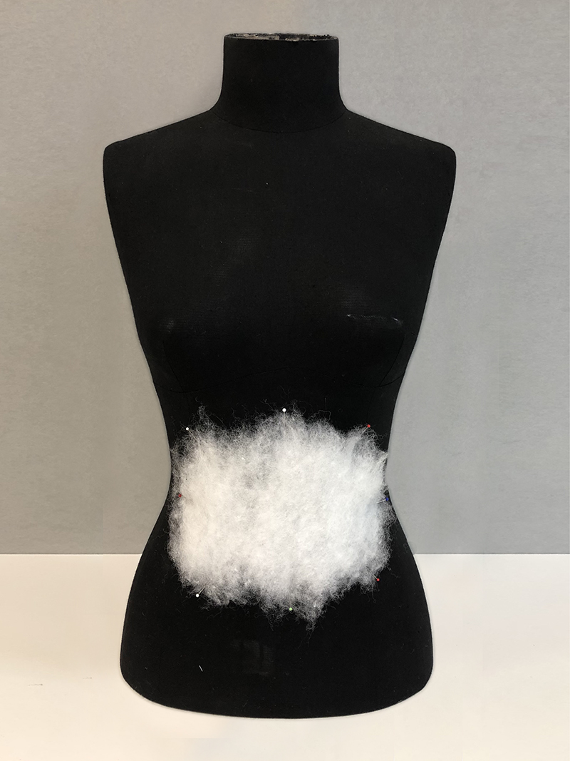 White dacron padding positioned on a black dressmaker's torso.