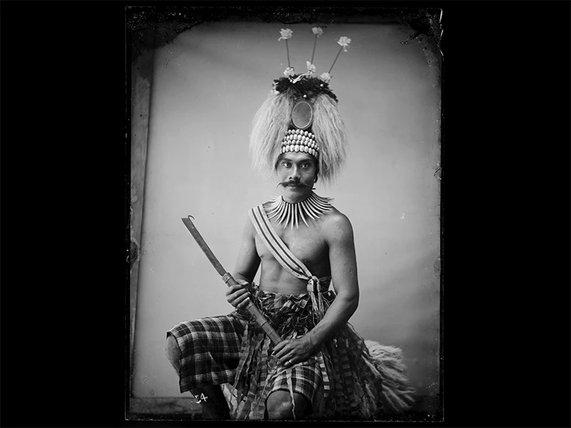 An old black and white photo of a Sāmoan chief in a headdress