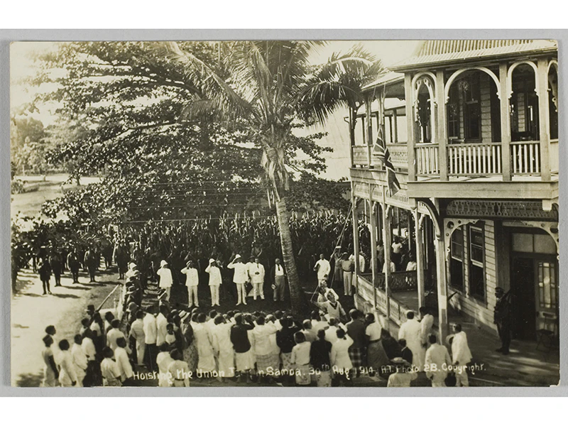 A sepia photo of people in uniform in Sāmoa hoisting a flag