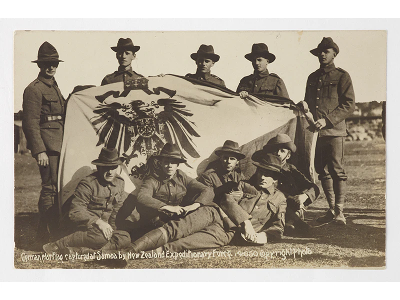 10 people in uniform standing and sitting around a flag