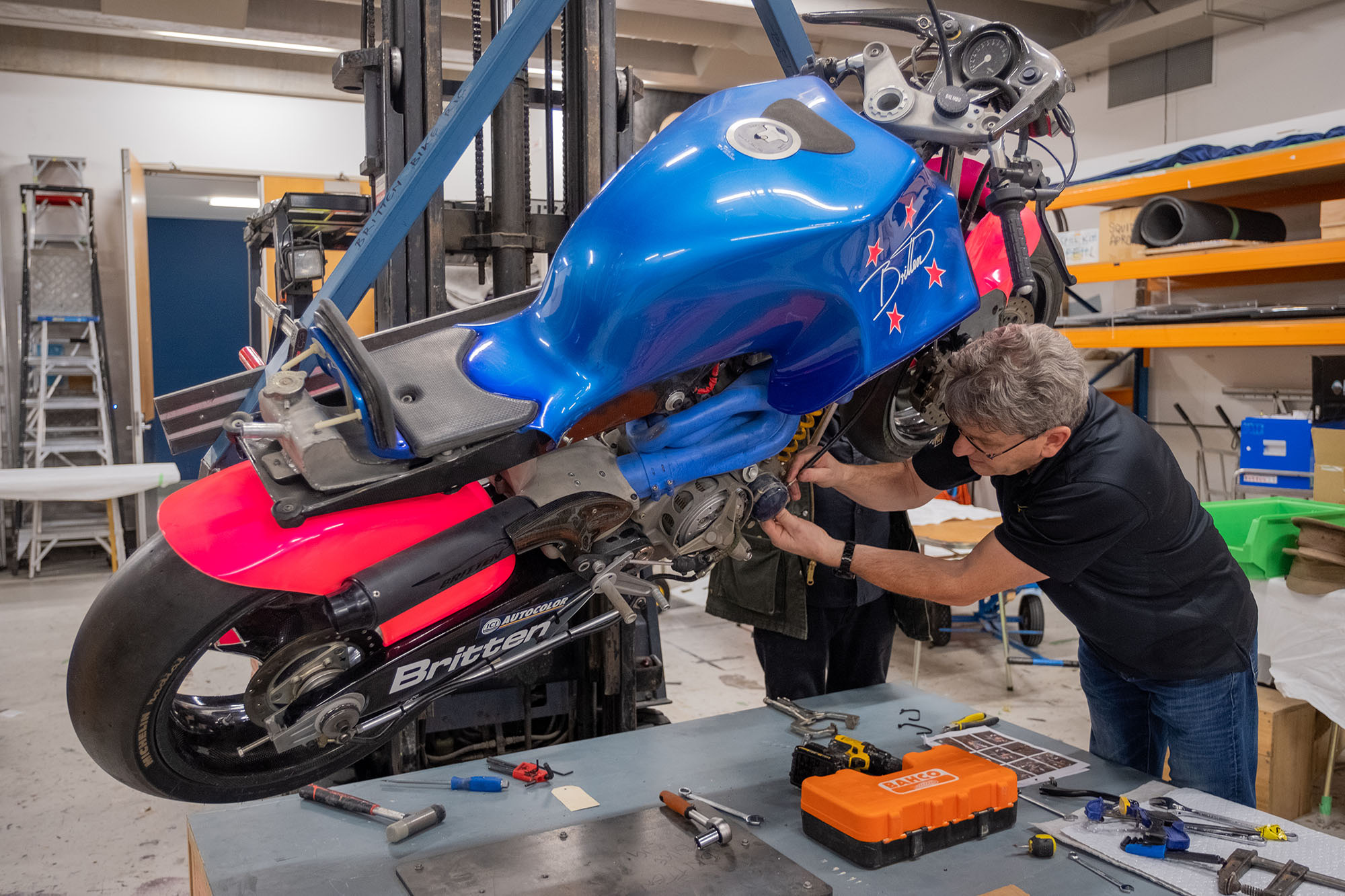 Craig looks at the Britten Bike engine while the bike is suspended from the forklift