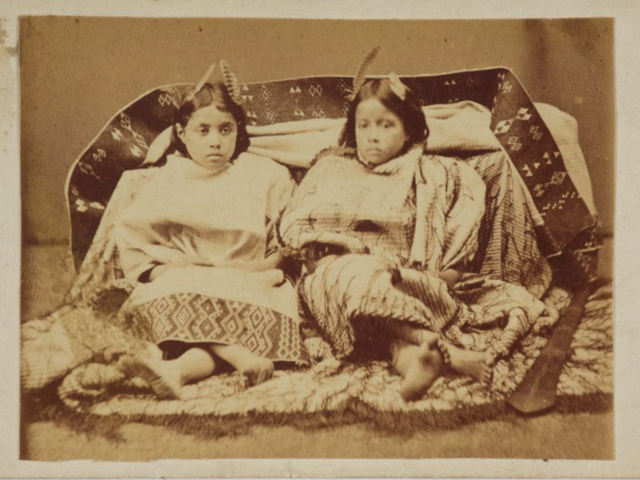 A sepia photo of two girls in a photography studio looking at the camera