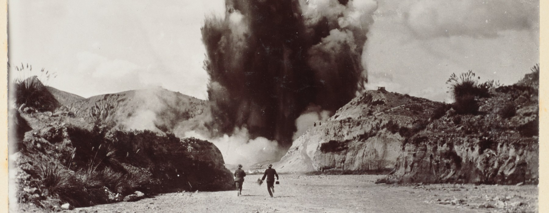 Two men stand and look at a Waimangu Geyser