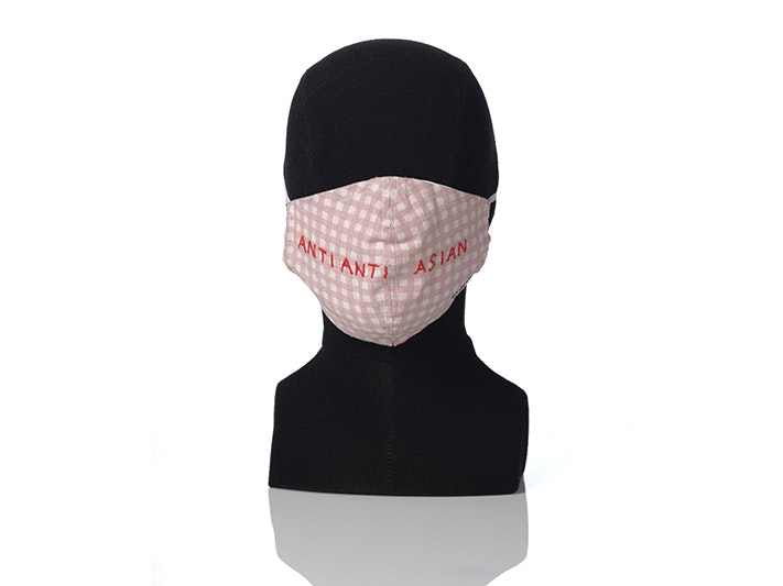 'Anti Anti Asian' embroidered mask, Hanna Shim; maker/artist; 2020; Auckland, Gift of Saera Chun, 2020. Te Papa (GH018376) A pink mask on a mannequin head with the words "anti anti Asian" embroidered on it