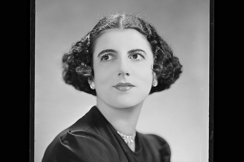 A black and white studio portrait photo of a woman looking up to her right