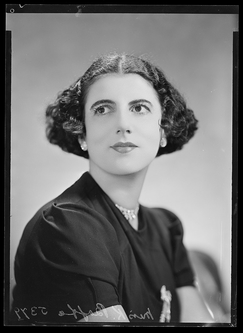 A black and white studio portrait photo of a woman looking up to her right