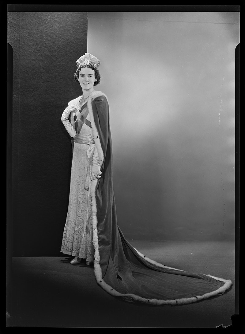 A black and white studio photo of a woman in a queen's costume