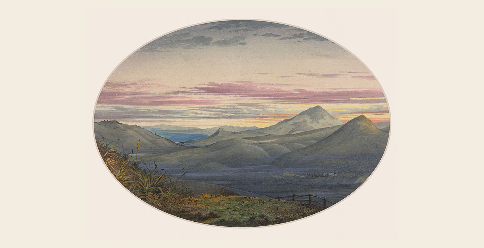 Vast view from high on a hill looking over an expansive plain with hills in the distance and a bay of water beyond. It is sunset and the sky is a blend of orange, purple, and white hues
