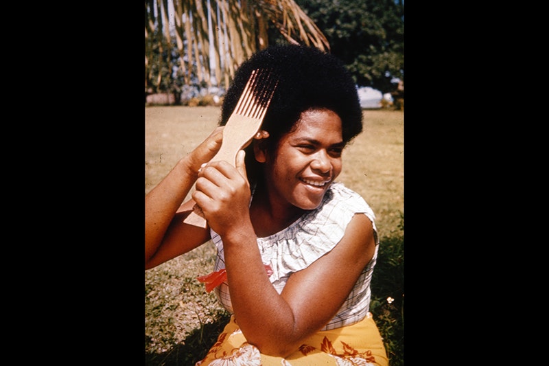 A woman combing her afro hair with a long-toothed comb