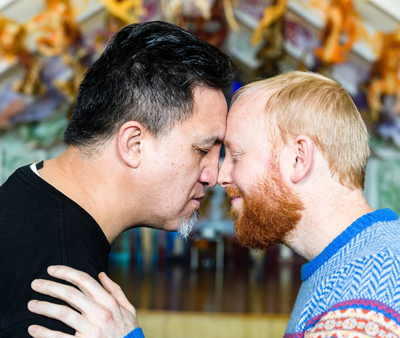 Two men press noses in greeting