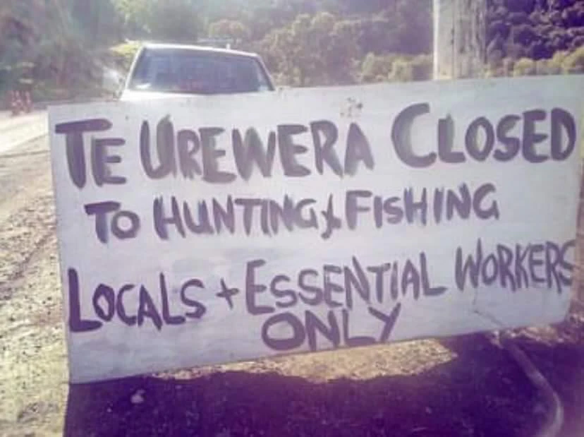 A handpainted sign on the side of the road with the words 'Te Urewera Closed to hunting and fishing. Locals and essential workers only'"